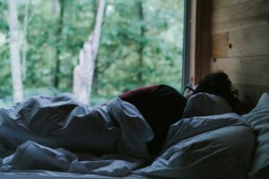 Person lying in bed covered with a blanket at night