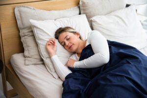 Woman sleeping peacefully in bed under a blue blanket